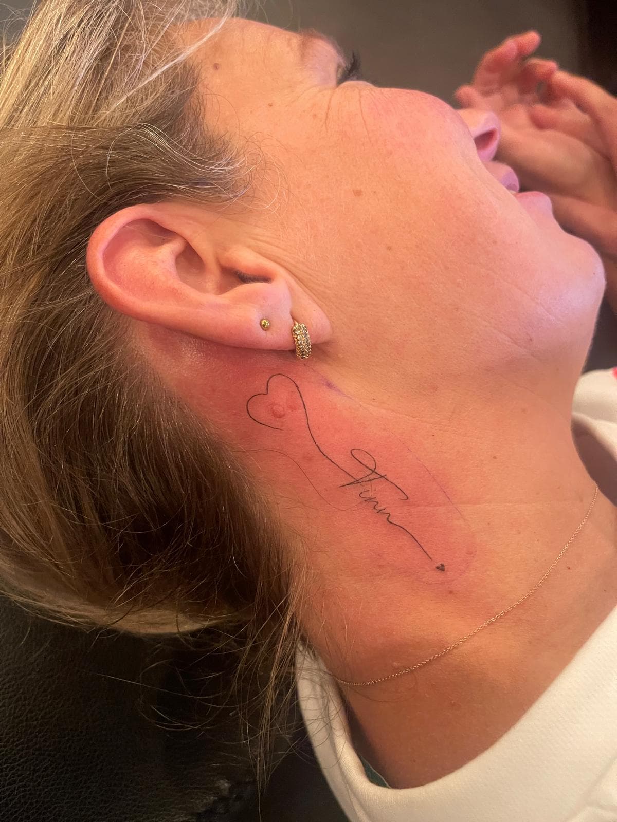 Fine line naam en hartje tattoo op nek