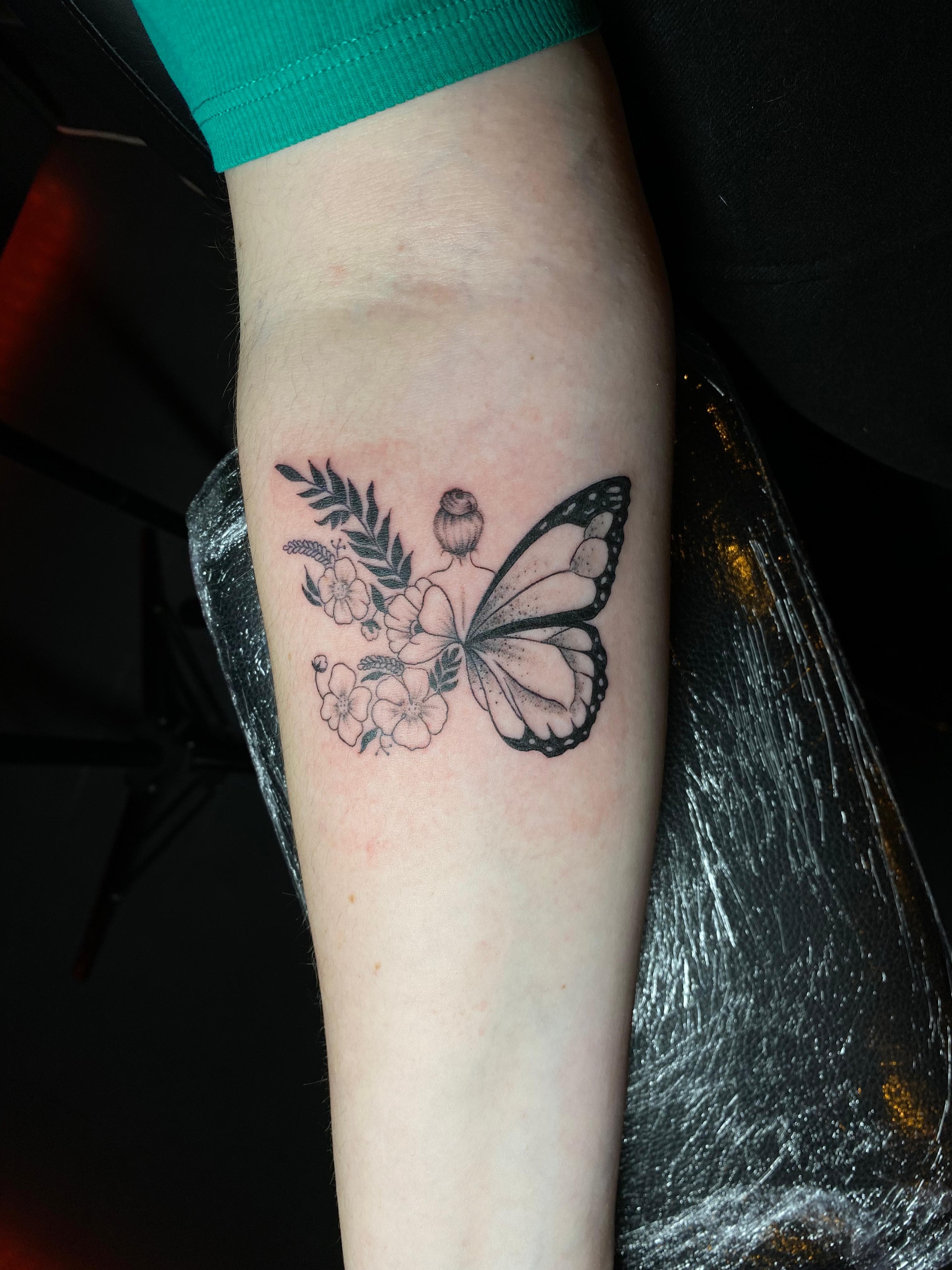 Fine line vlinder met bloemen tattoo op onderarm